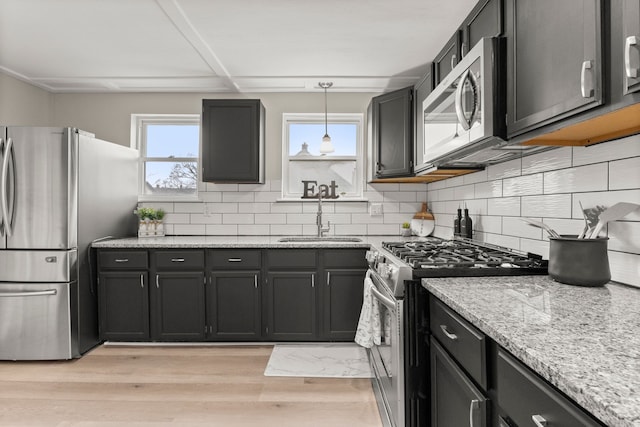 kitchen featuring light stone countertops, a sink, stainless steel appliances, and backsplash