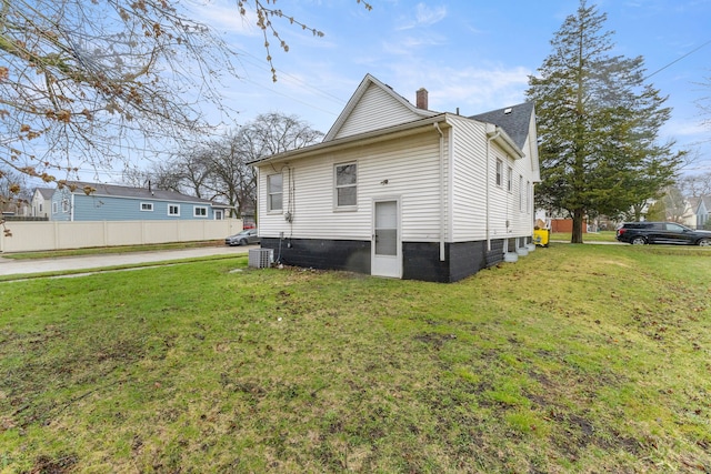 rear view of property with a chimney, fence, and a lawn