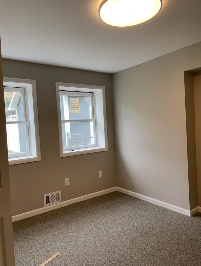 empty room featuring carpet flooring, baseboards, and visible vents