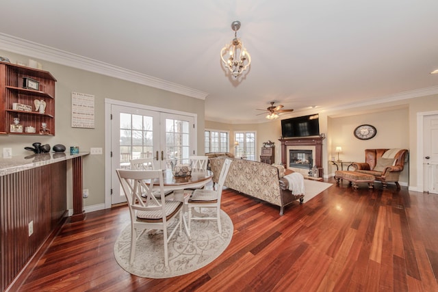 5050 Pleasant Lake Rd, Ann Arbor, MI 48103 - dining space featuring a glass covered fireplace, ceiling fan, crown molding, dark wood-style floors, and a chandelier