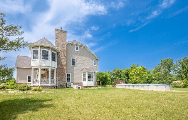 5050 Pleasant Lake Rd, Ann Arbor, MI 48103 - back of property with a yard, a chimney, ceiling fan, and an outdoor pool