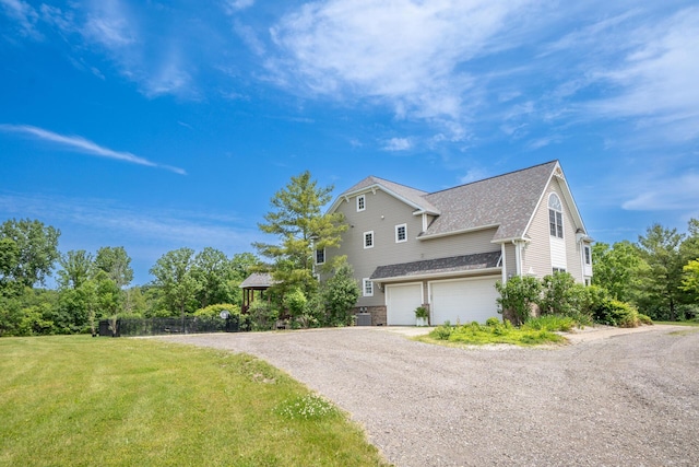 5050 Pleasant Lake Rd, Ann Arbor, MI 48103 - view of home's exterior featuring a garage, dirt driveway, roof with shingles, and a yard