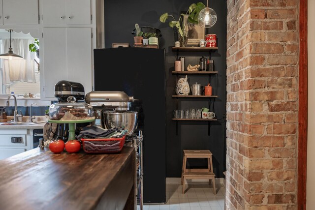 kitchen featuring white cabinets, a sink, butcher block countertops, and light tile patterned floors