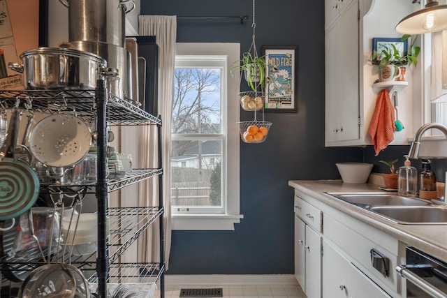 kitchen with dishwasher, light countertops, a sink, and white cabinetry