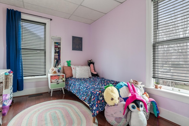 bedroom featuring a drop ceiling, visible vents, baseboards, and wood finished floors