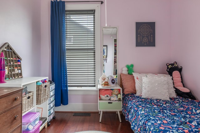bedroom with multiple windows, visible vents, wood finished floors, and baseboards