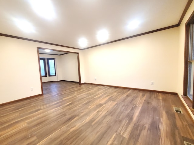 unfurnished room with baseboards, ornamental molding, visible vents, and wood finished floors