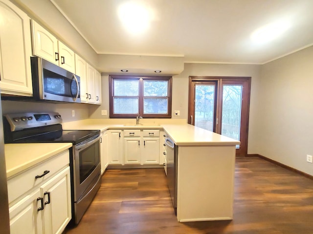kitchen with dark wood-style floors, a healthy amount of sunlight, a peninsula, and appliances with stainless steel finishes