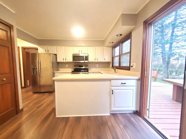 kitchen with white cabinetry, dark wood-type flooring, a sink, a peninsula, and appliances with stainless steel finishes