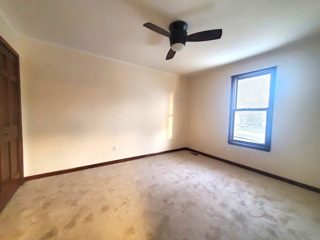empty room with a ceiling fan, baseboards, and light colored carpet