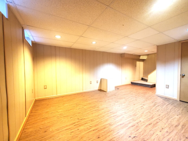 finished basement with stairway, recessed lighting, baseboards, light wood-style floors, and a paneled ceiling