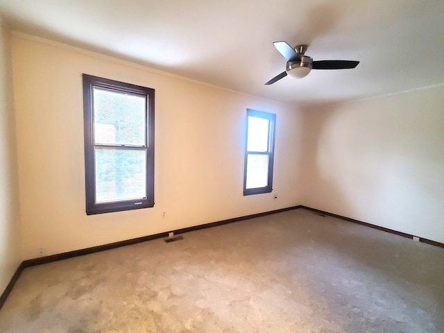 empty room featuring baseboards, visible vents, carpet flooring, and a ceiling fan