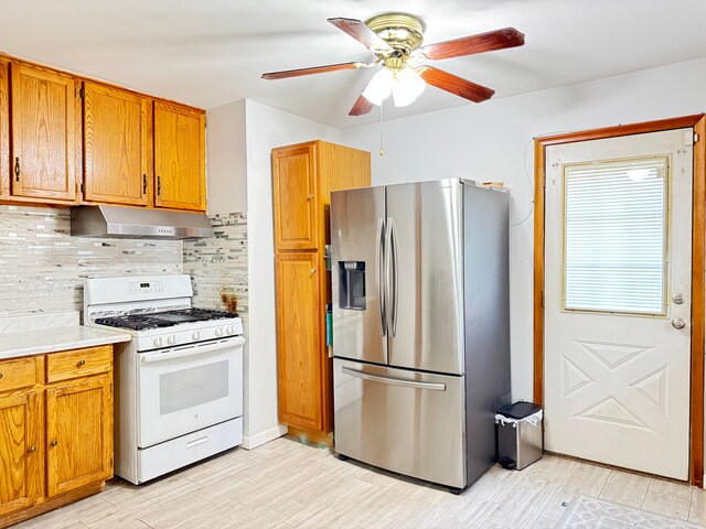 24275 Valley Ave, Eastpointe, MI 48021 - kitchen featuring stainless steel fridge with ice dispenser, white range with gas cooktop, under cabinet range hood, brown cabinets, and backsplash