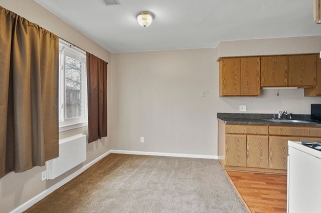 kitchen with gas range gas stove, a sink, dark countertops, and baseboards