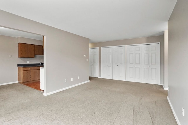 interior space with baseboards, two closets, and light carpet