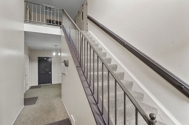 staircase featuring baseboards, a high ceiling, and carpet floors