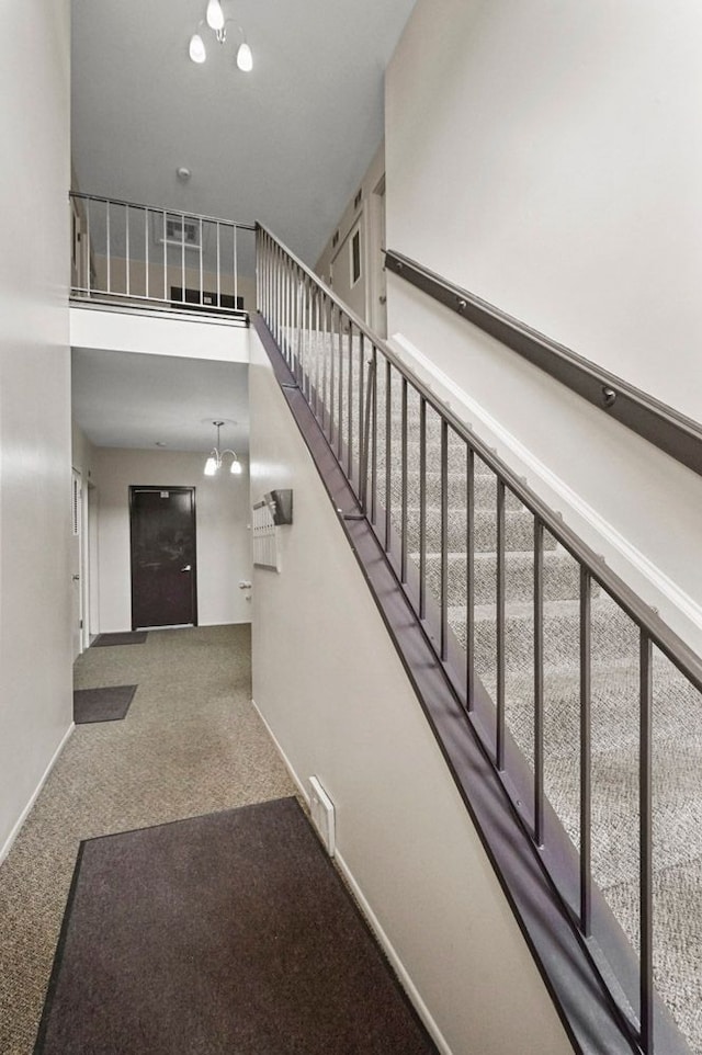 stairs with baseboards, carpet flooring, a towering ceiling, and visible vents