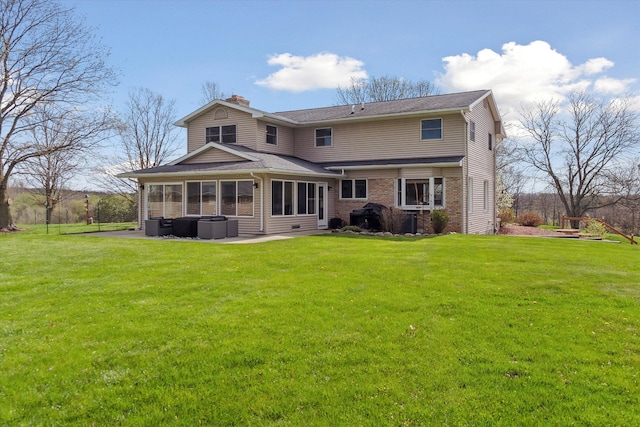back of house with a patio, a chimney, brick siding, and a lawn