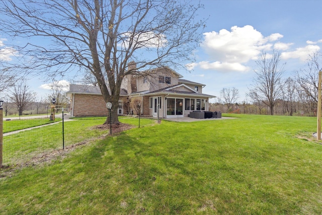 back of house with a sunroom, a chimney, a lawn, and brick siding