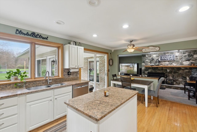 kitchen with ornamental molding, a fireplace, ceiling fan, dishwasher, and a sink