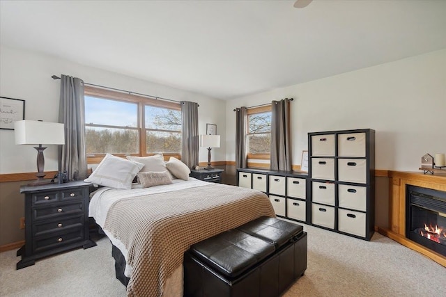 bedroom featuring light carpet and a glass covered fireplace