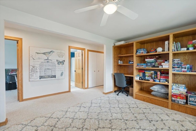 carpeted office space featuring baseboards and ceiling fan