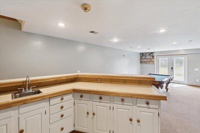 kitchen featuring french doors, white cabinetry, carpet floors, visible vents, and a sink