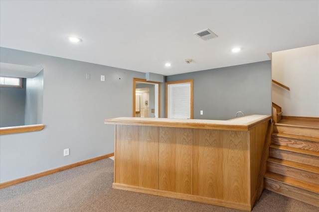 bar with indoor wet bar, visible vents, stairway, light carpet, and baseboards