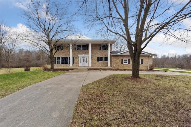 greek revival house with a front yard, curved driveway, and brick siding