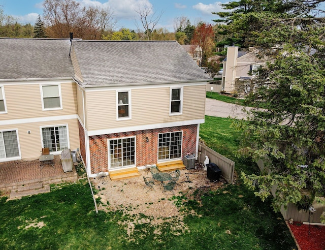 rear view of house featuring roof with shingles, a yard, fence, central AC, and brick siding