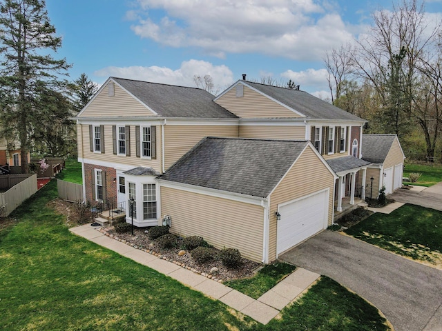 view of front of property featuring a front yard, driveway, a shingled roof, and an attached garage