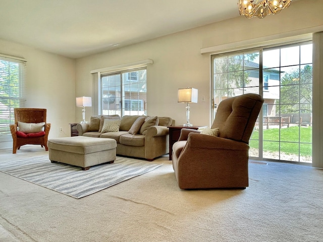 carpeted living area featuring visible vents, a healthy amount of sunlight, and a notable chandelier