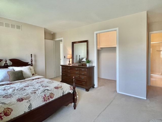 bedroom with a closet, visible vents, light colored carpet, and a spacious closet