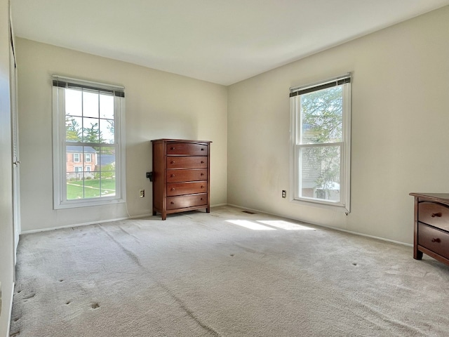 unfurnished bedroom with multiple windows, carpet floors, and baseboards