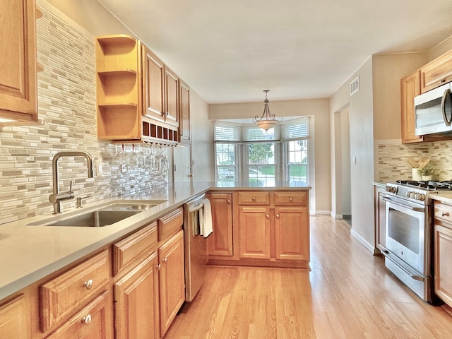 kitchen featuring a sink, appliances with stainless steel finishes, visible vents, light wood-type flooring, and a peninsula