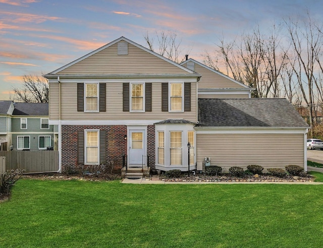 back of property with fence, entry steps, and a lawn