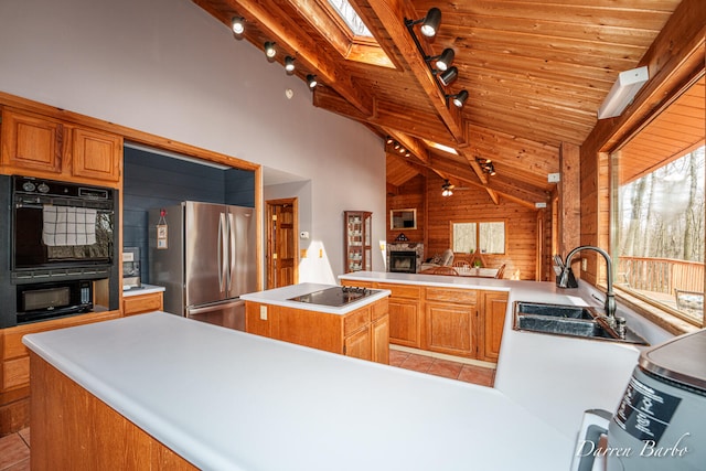 3770 Pine Ln, Saranac, MI 48881 - kitchen featuring black appliances, a kitchen island, wood walls, a peninsula, and light countertops