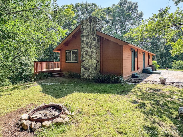 3770 Pine Ln, Saranac, MI 48881 - view of side of property featuring an outdoor fire pit, a wooden deck, a patio, a chimney, and a yard