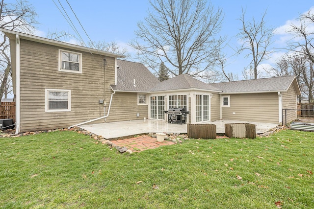 rear view of house with a patio, a shingled roof, fence, and a lawn