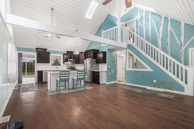 kitchen with light countertops, dark wood-style flooring, stainless steel appliances, a center island, and a ceiling fan