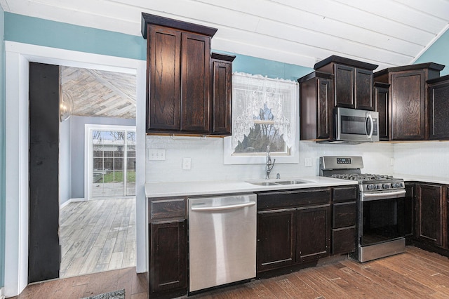 kitchen featuring light countertops, wood finished floors, stainless steel appliances, a sink, and backsplash