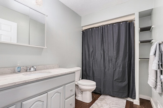 bathroom featuring toilet, wood finished floors, vanity, and a textured ceiling