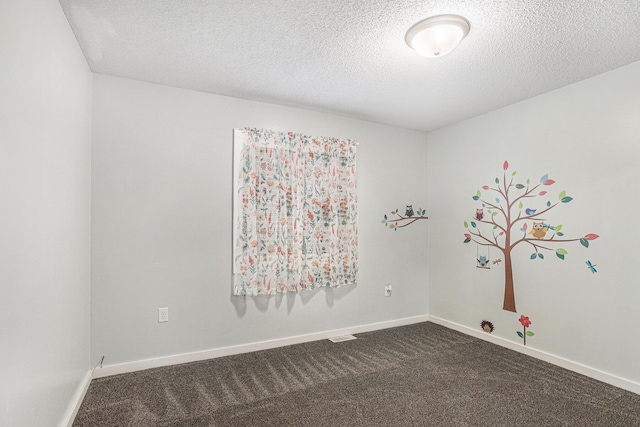 empty room with baseboards, dark carpet, and a textured ceiling