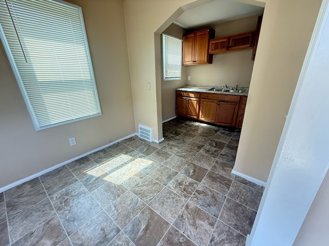 8909 Penrod St, Detroit, MI 48228 - kitchen with stone finish floor, light countertops, a sink, baseboards, and visible vents