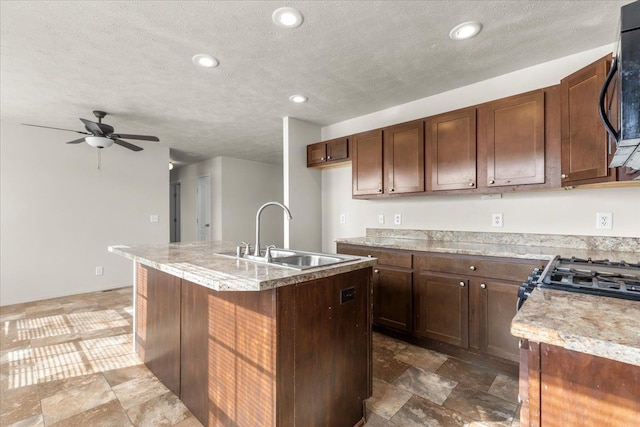 kitchen with a textured ceiling, a center island with sink, a sink, a ceiling fan, and black microwave