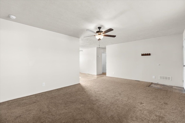 spare room featuring a textured ceiling, visible vents, a ceiling fan, and light colored carpet