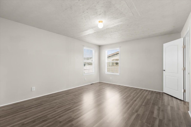 spare room with dark wood-type flooring and a textured ceiling