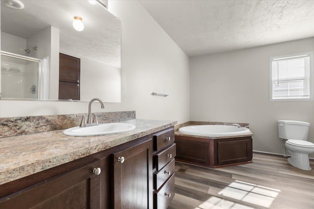 bathroom with vanity, toilet, a textured ceiling, a stall shower, and a garden tub