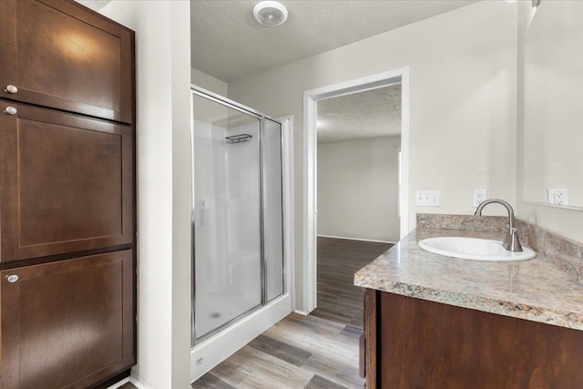 bathroom with wood finished floors, vanity, a stall shower, and a textured ceiling