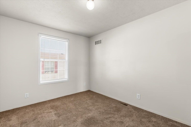 empty room with carpet flooring, a textured ceiling, and visible vents